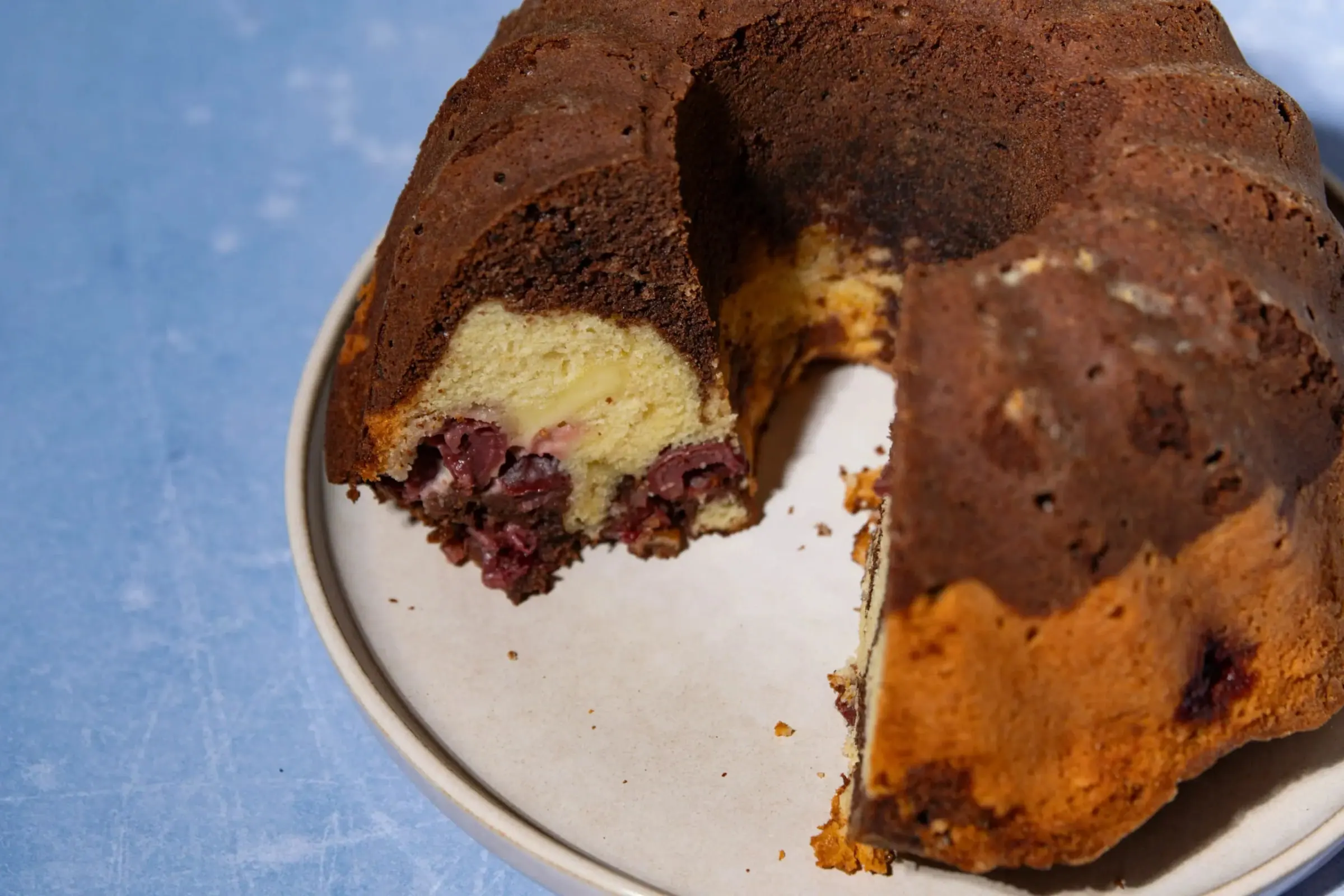 Angeschnittener Guglhupf mit Kirschen und Cheesecake-Füllung