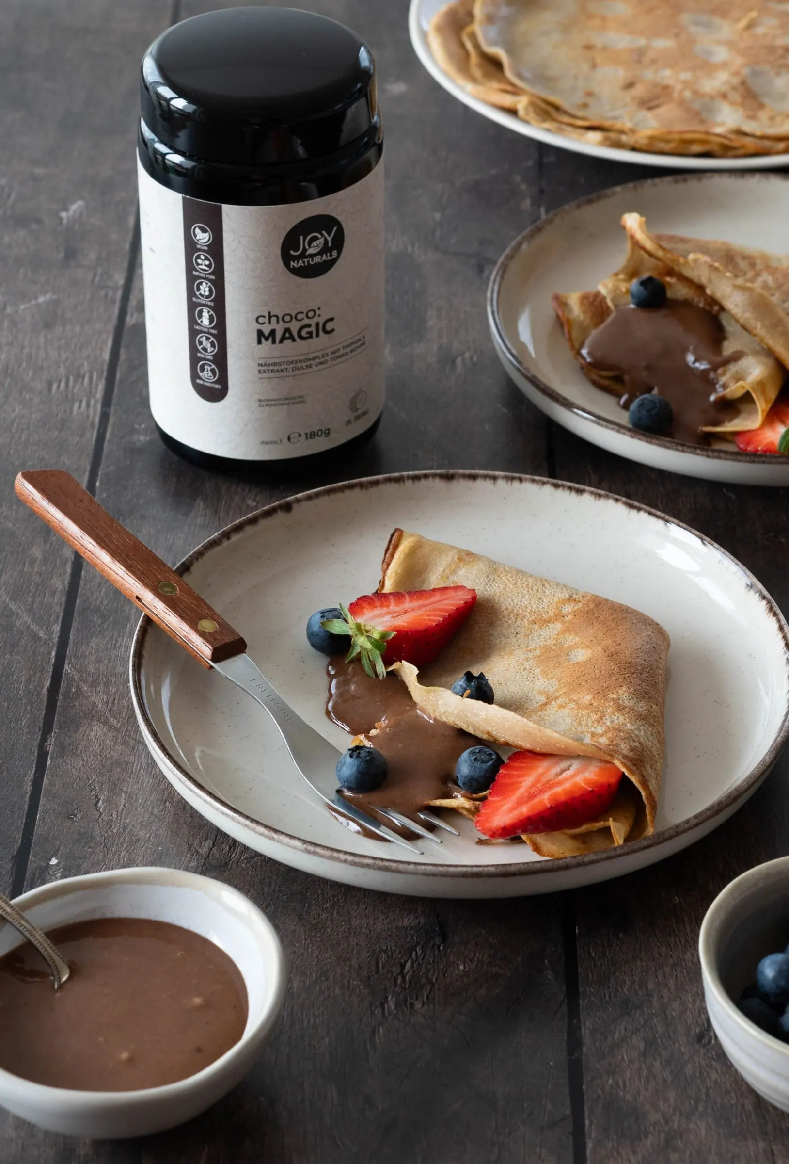 Crêpes mit Schokocreme und Beeren, dahinter das Produktglas