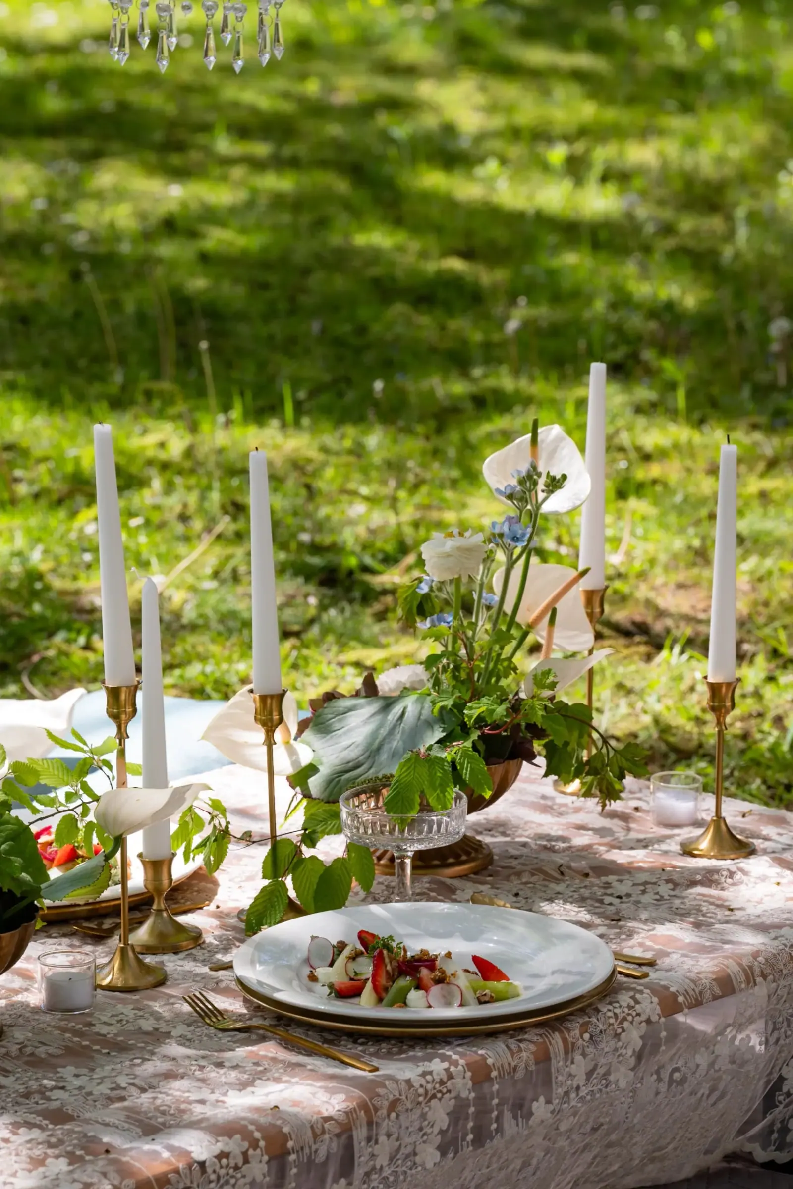 Gedeckte Tafel mit Kerzen und Blumen auf einer Wiese