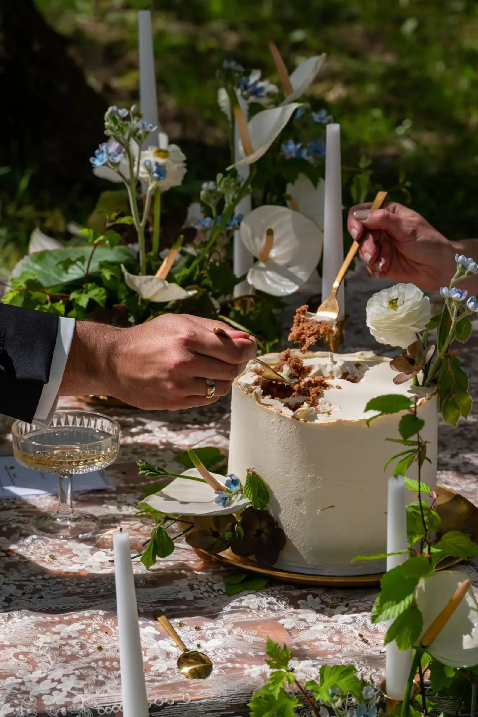Eine Hochzeitstorte wird an der Tafel im Garten angeschnitten